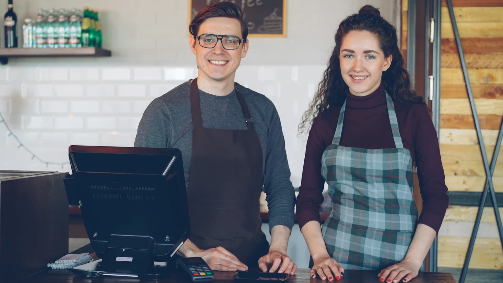 Deux commerçants souriants derrière le comptoir de leur boutique