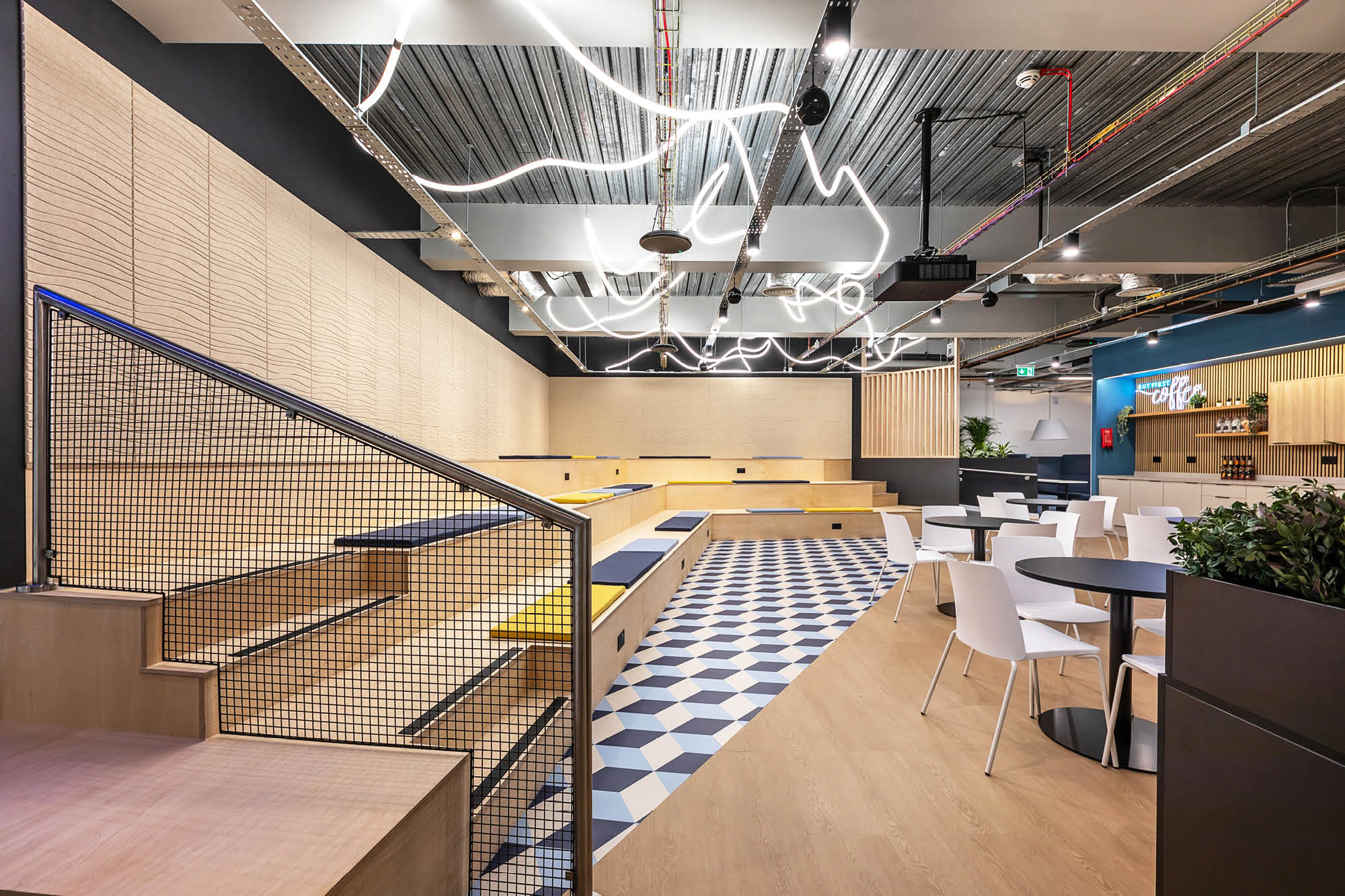 Modern interior of cafe with geometric design elements. Features stepped seating with wood texture.