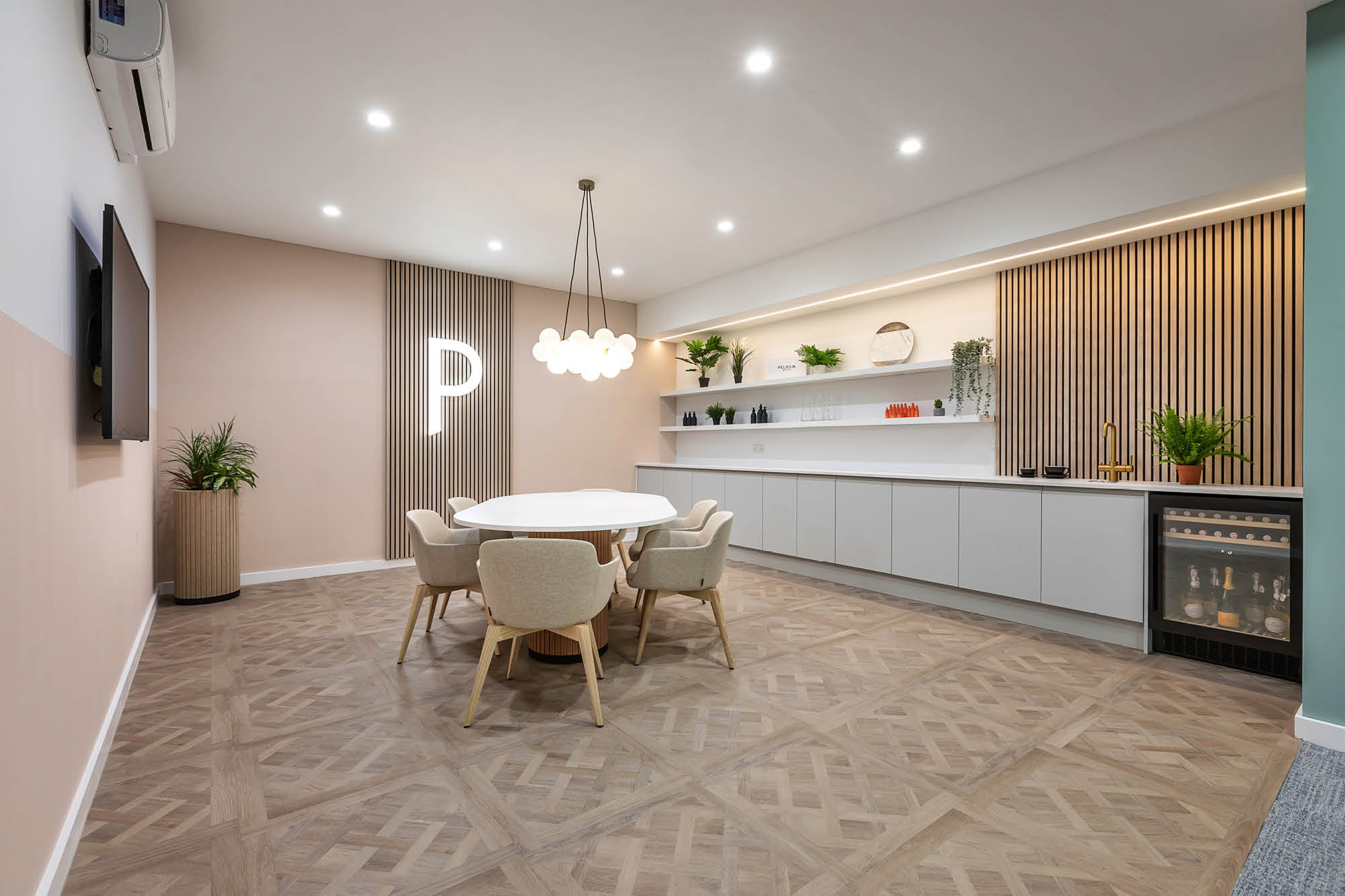 Modern dining area with a round table, five beige chairs, and pendant lighting.
