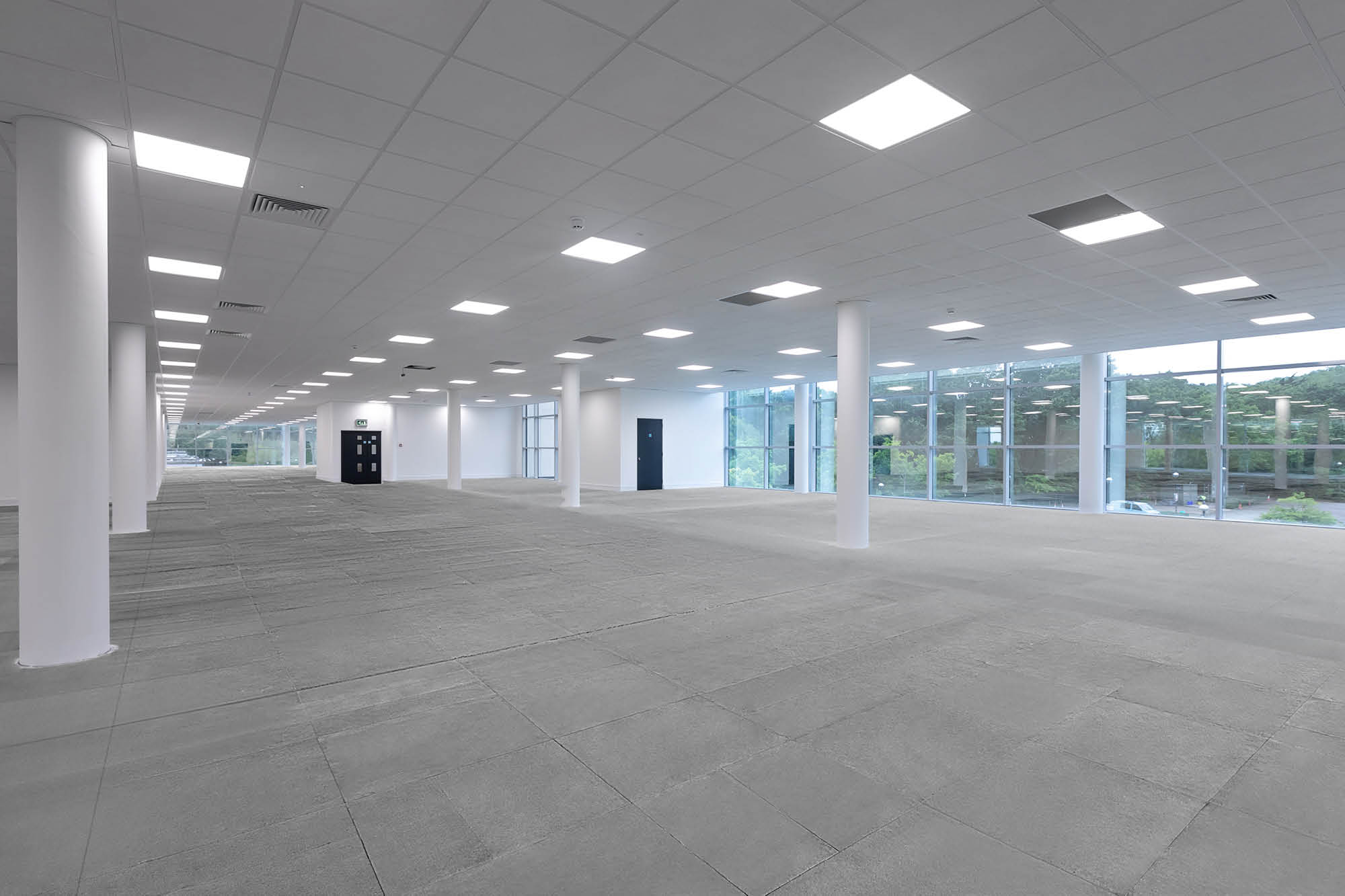 Spacious, empty office interior with large windows along one wall, allowing natural light.