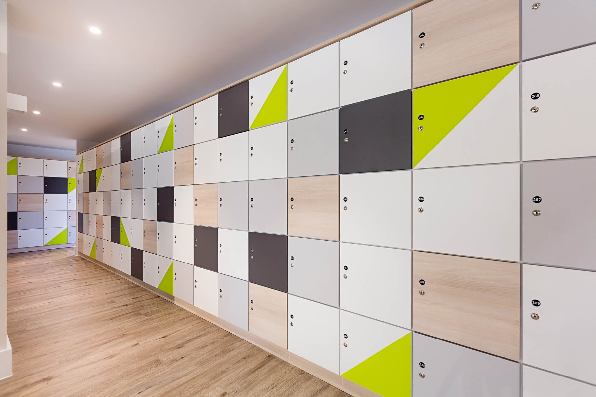 A long hallway with a wall of lockers featuring a geometric design in white, gray, beige, and lime green.