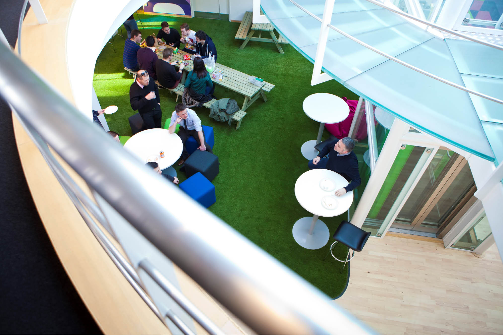 View from above of people socializing in a modern indoor area with green turf flooring.