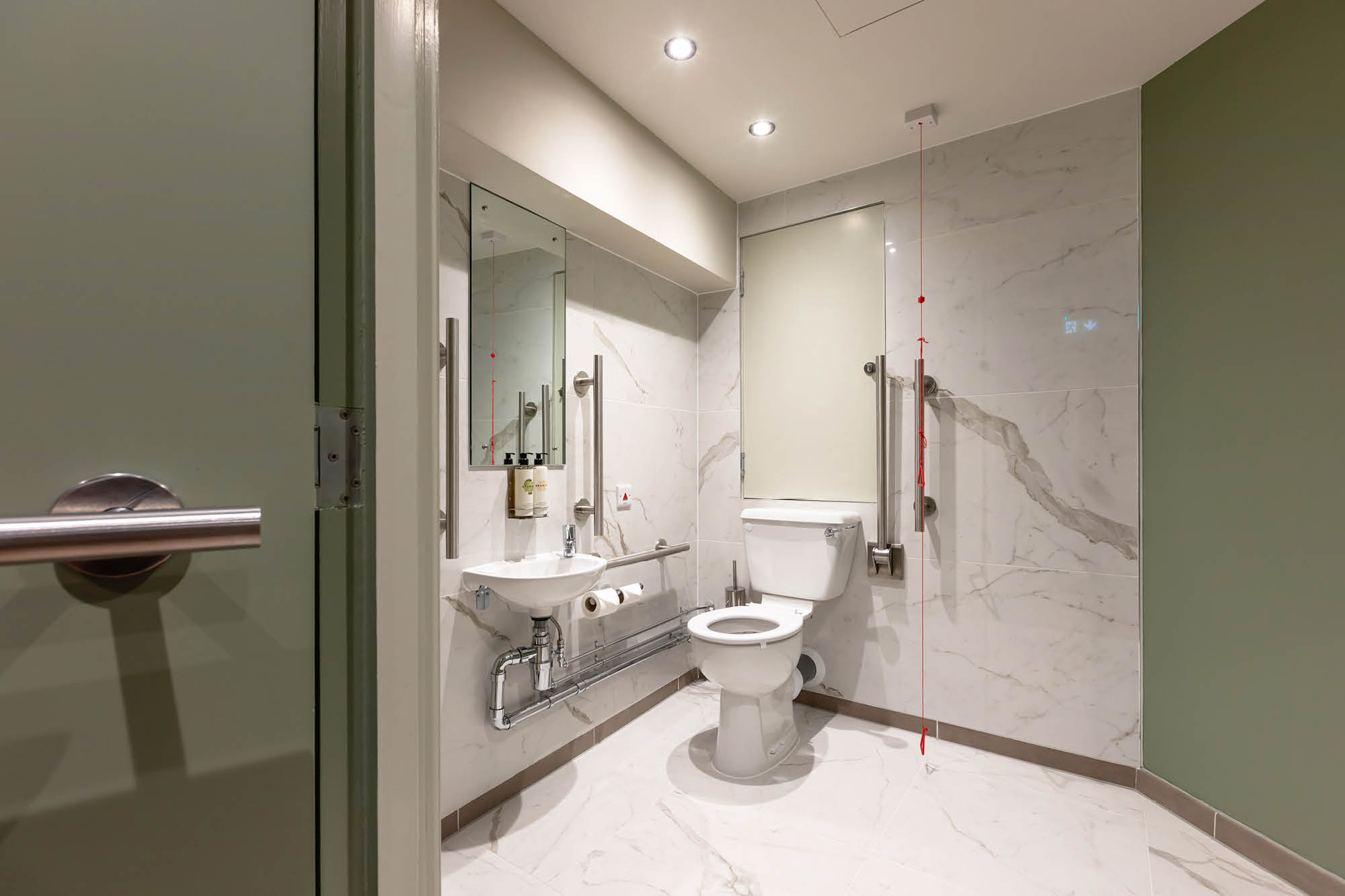 Accessible bathroom with ADA-compliant features such as handrails beside a toilet and sink.