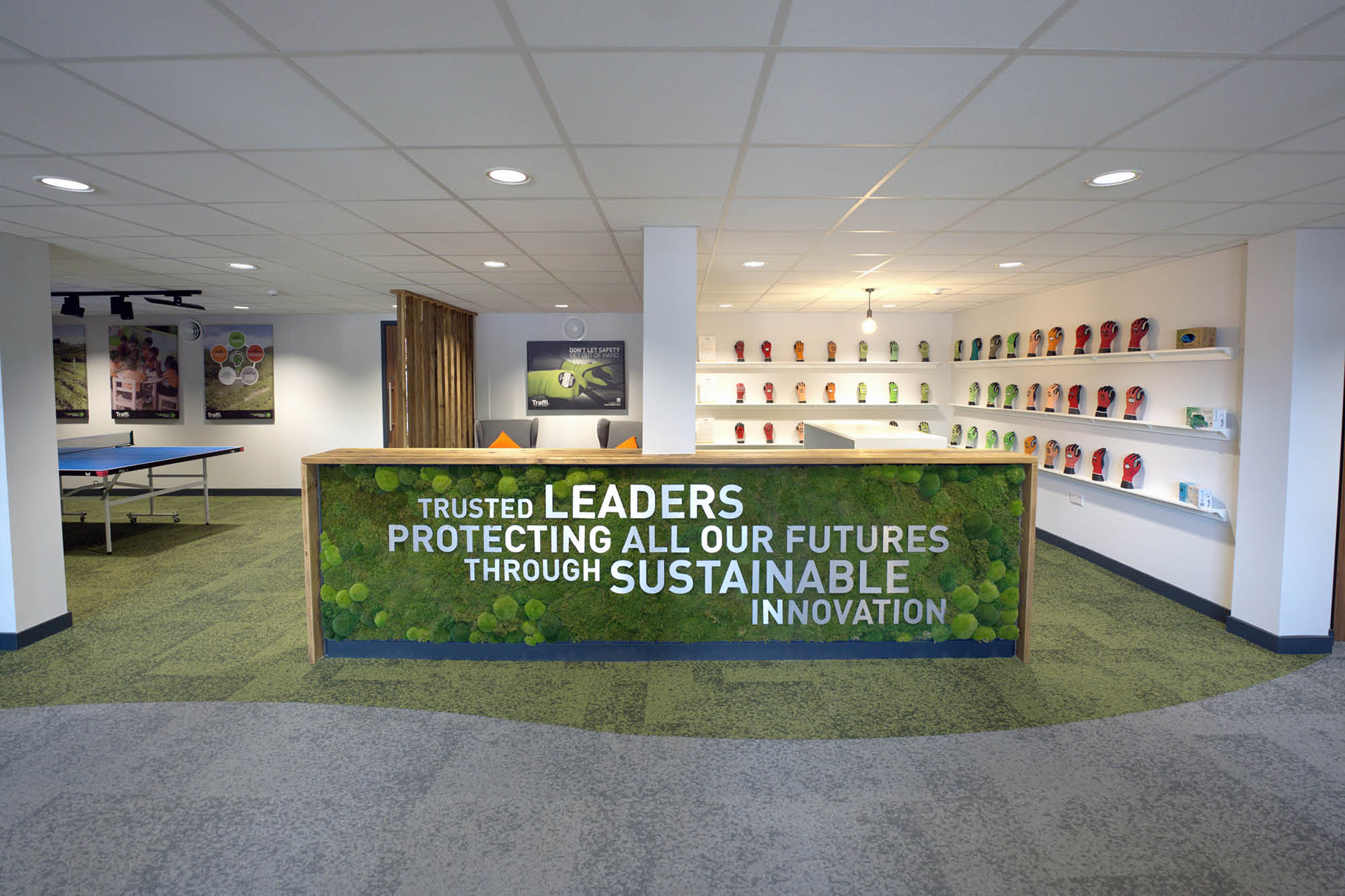 Modern lobby with a green, plant-covered counter displaying the text: Trusted leaders protecting all our futures through sustainable innovation.