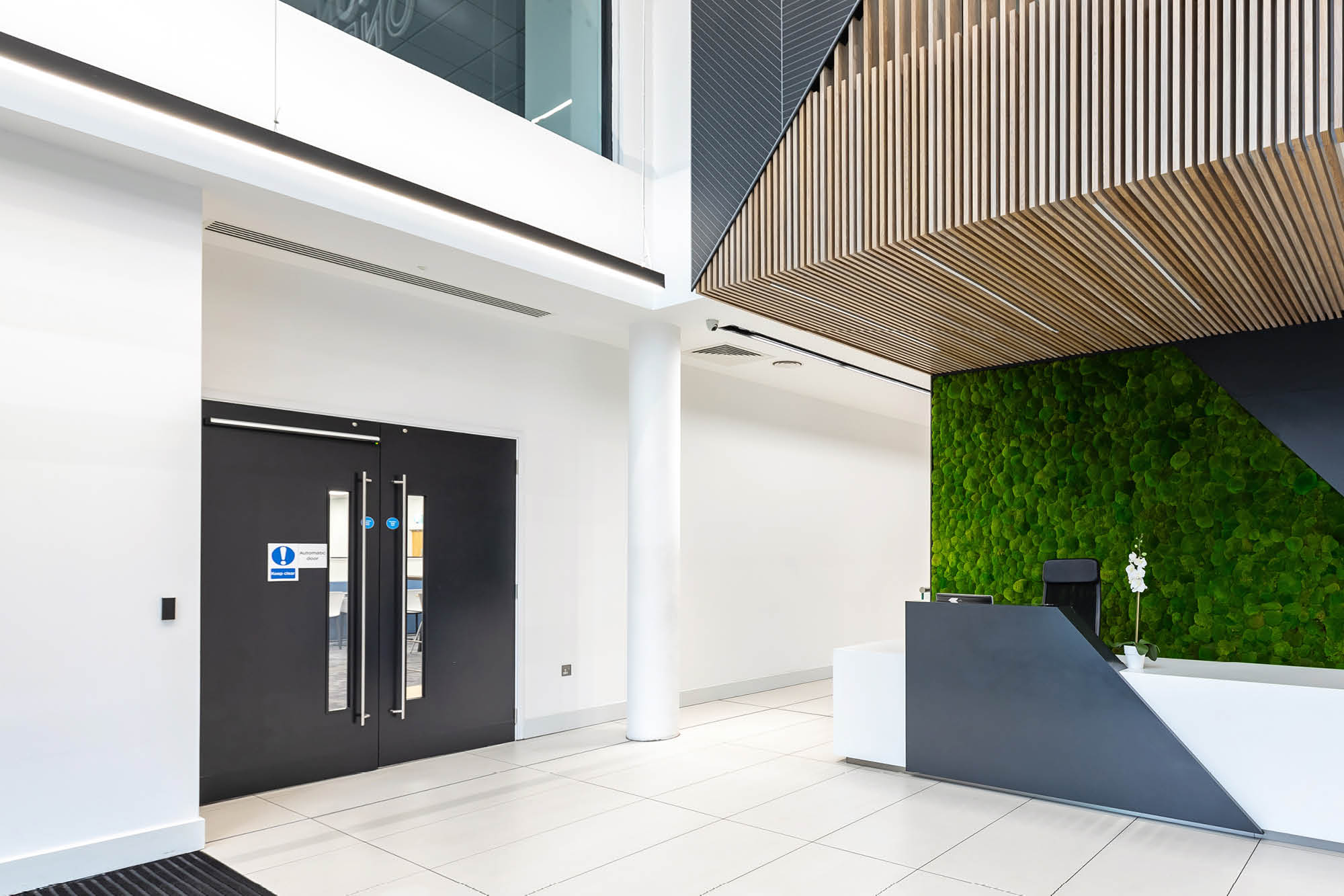 Reception area with black doors leading to office space.