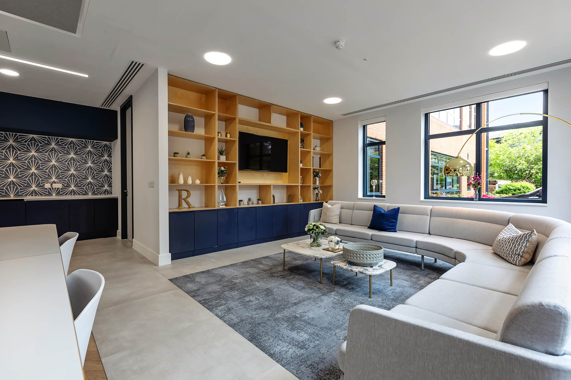 Modern living room with a large sectional sofa, round coffee tables, and a built-in wood shelving.