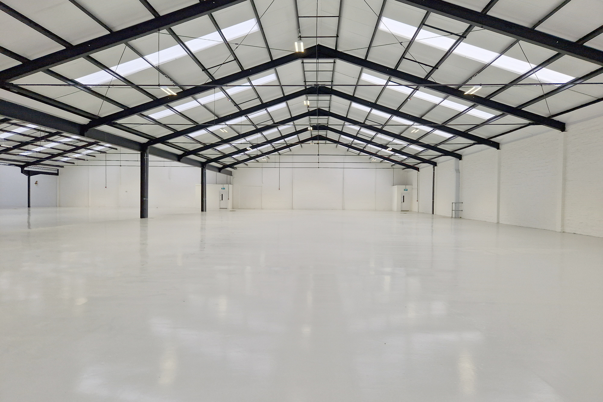 Open warehouse industrial space with clean glossed floor and lighting.