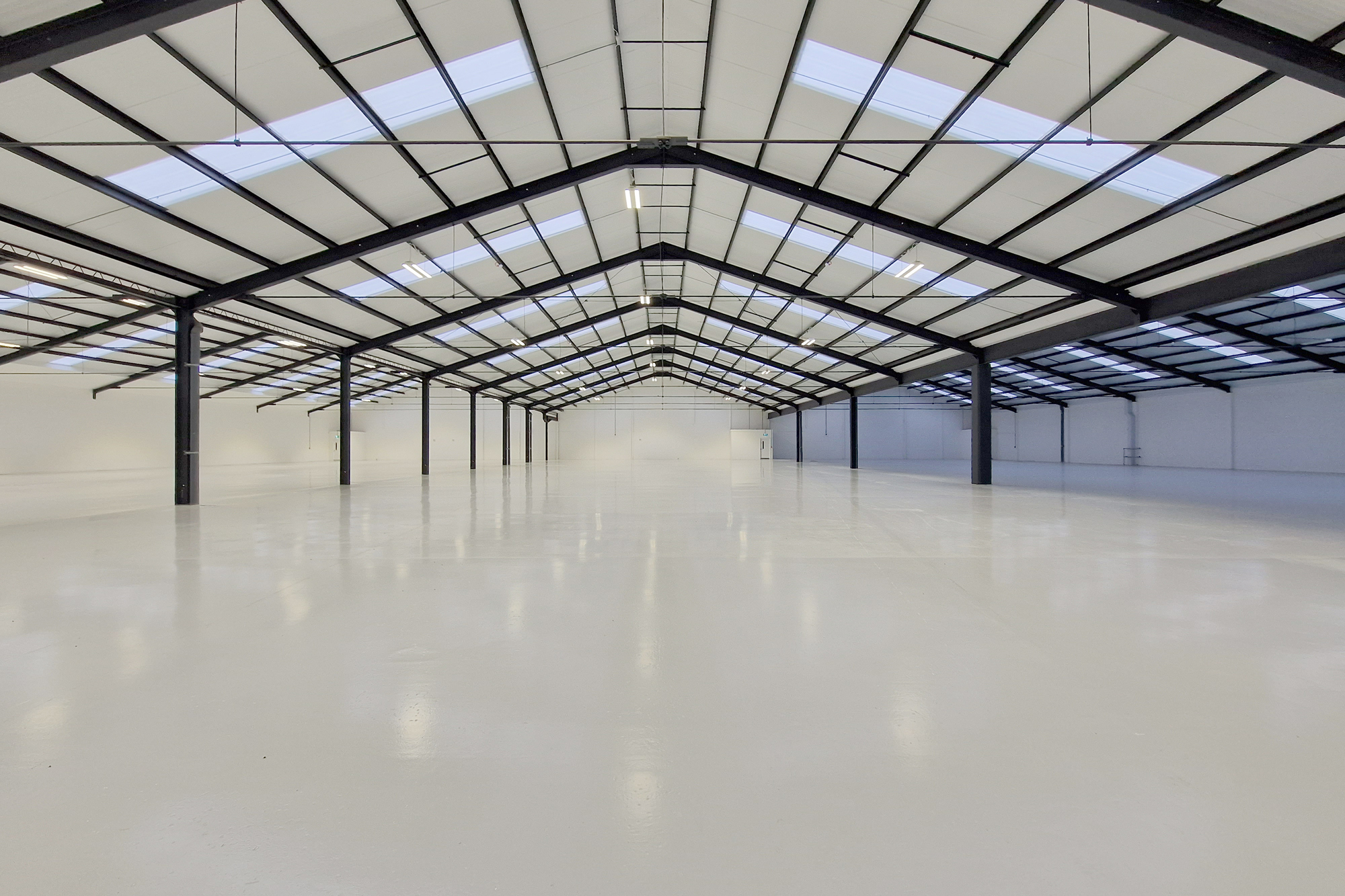 Open warehouse industrial space with clean glossed floor and luminous lighting.