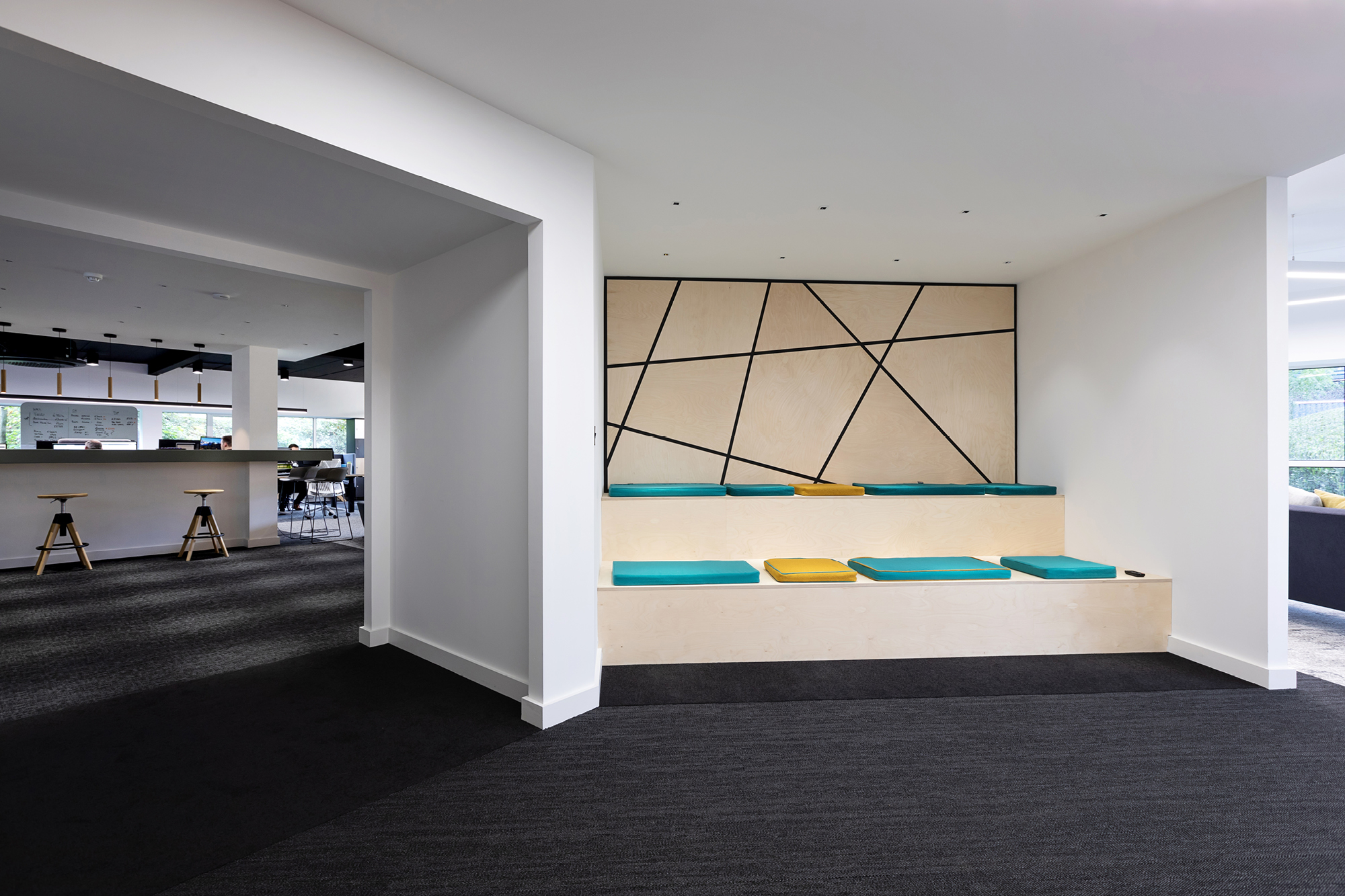 Modern office entrance with Gen II logo on a wall. There are plants in a small planter, exposed ceiling pipes, and a large window.