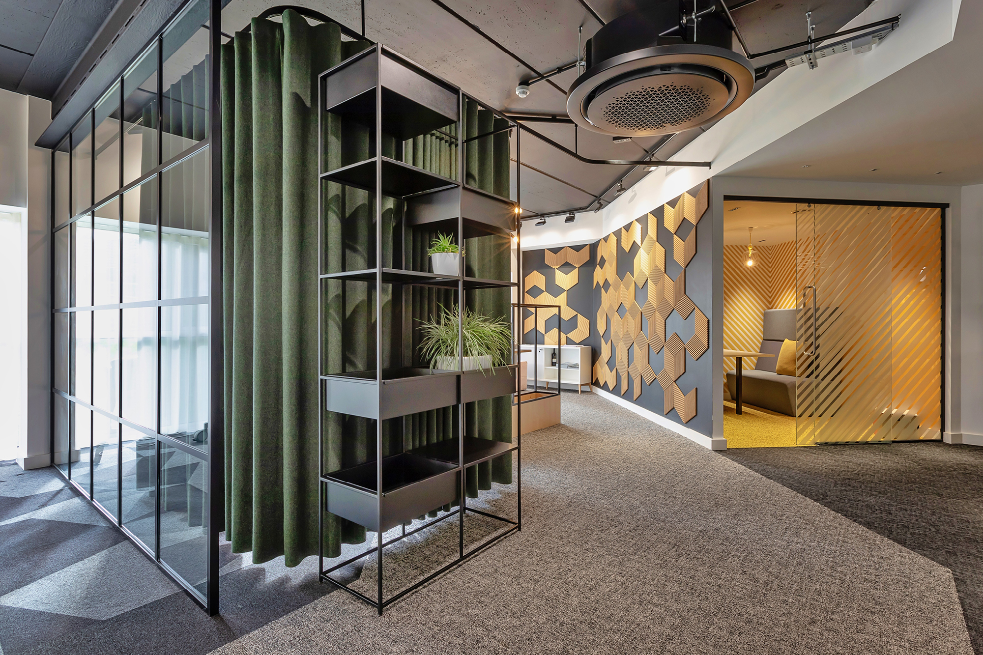 Modern office lobby featuring potted green plants on the left and a glass entrance on the right.