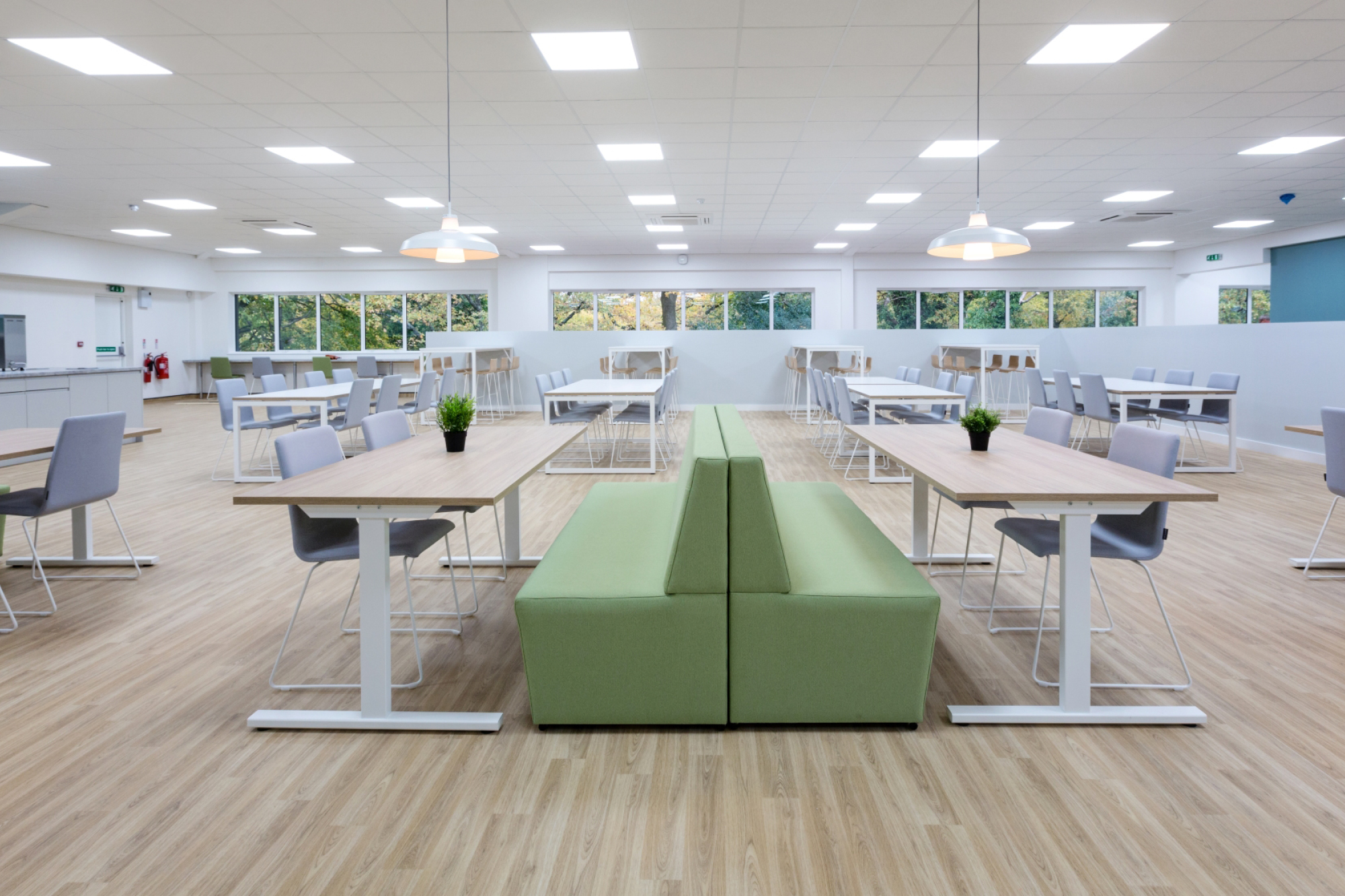 Open area breakout ad kitchen seating area with green sofas and grey chairs.