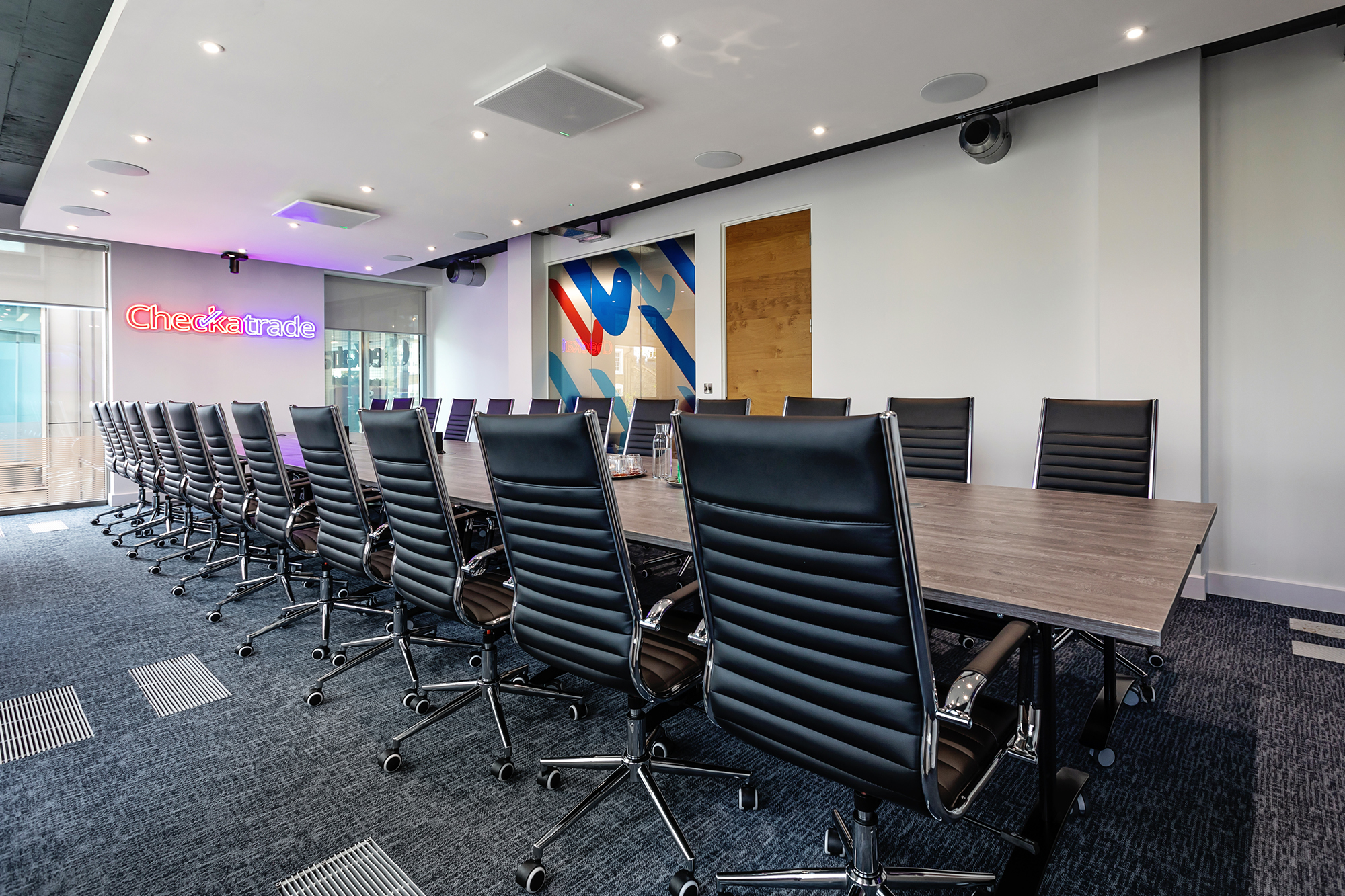 Executive boardroom with long brown oak table and checkatrade logo.
