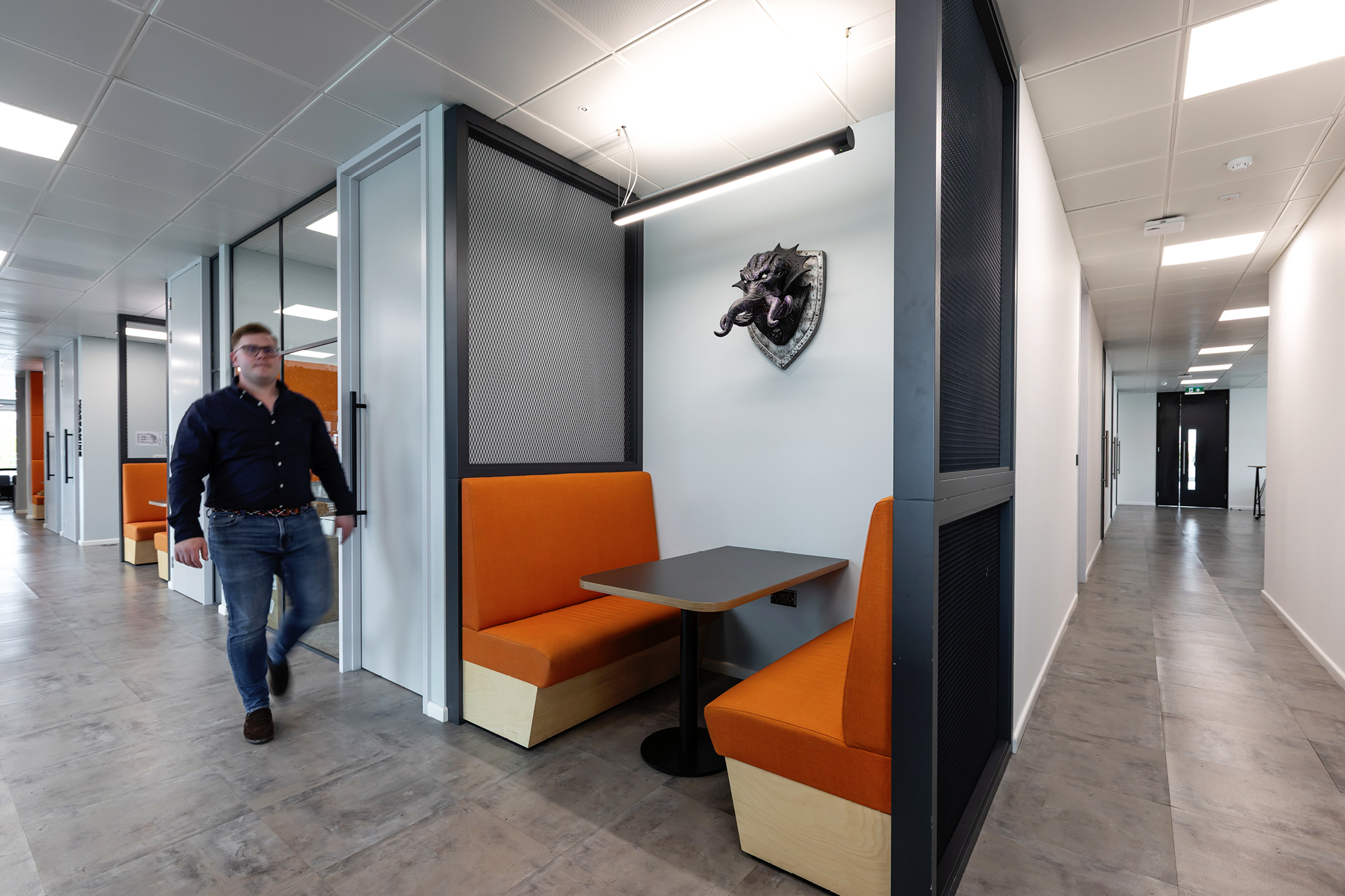 A modern office space with rows of workstations. Each desk has a computer monitor and an ergonomic chair.