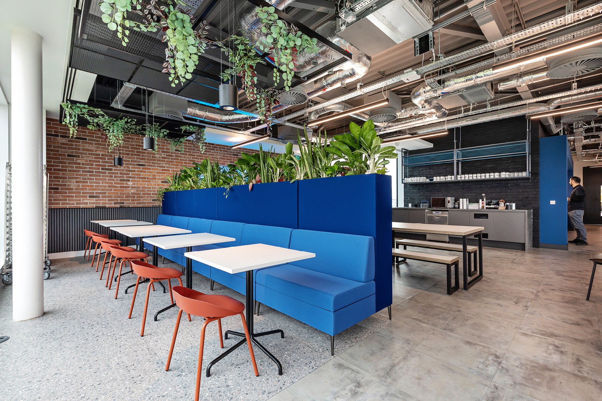 Modern interior of a cafe with geometric design elements. Features stepped seating with wood texture, black chairs.