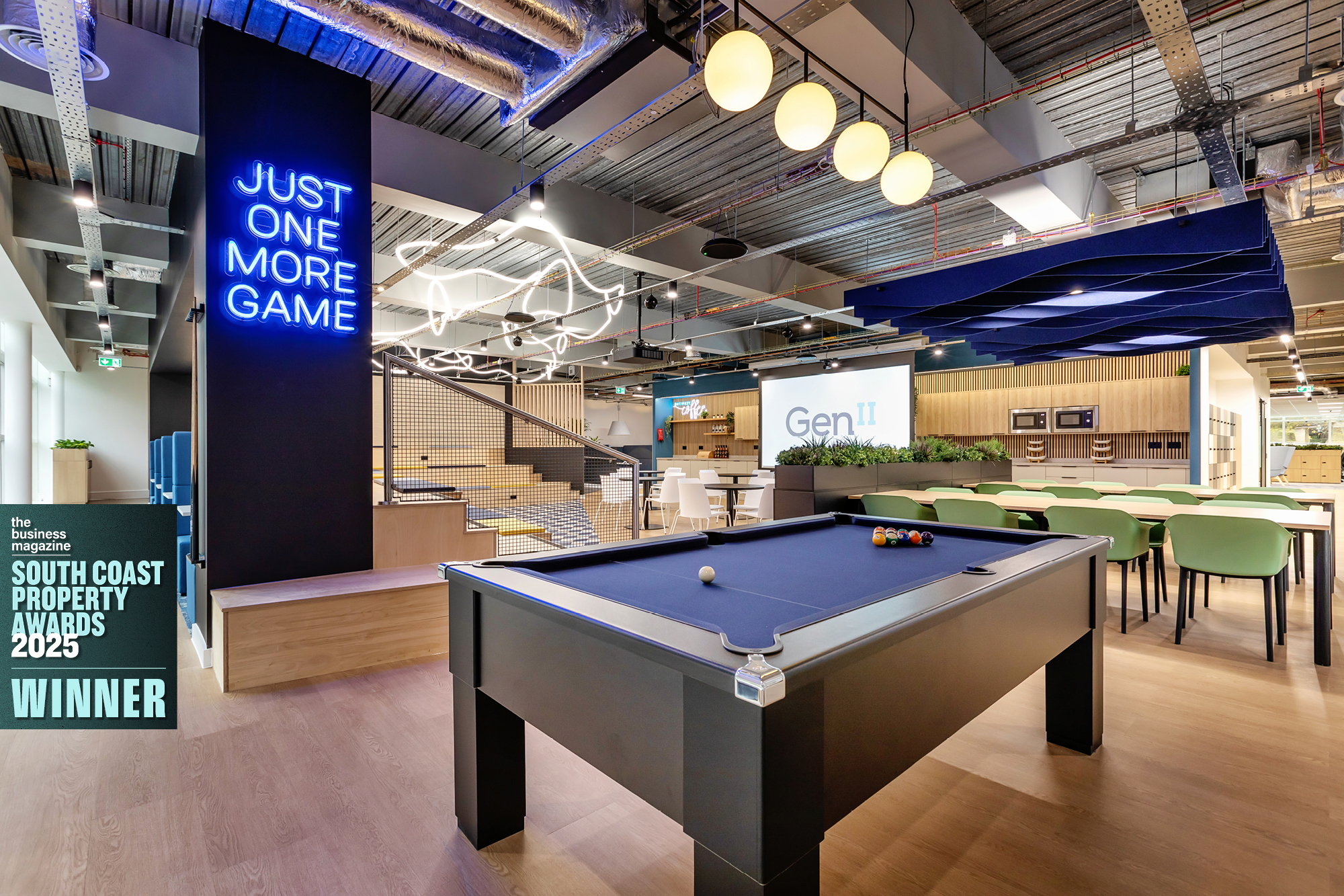 Modern office space with a black pool table in the foreground. Neon sign reads Just One More Game.