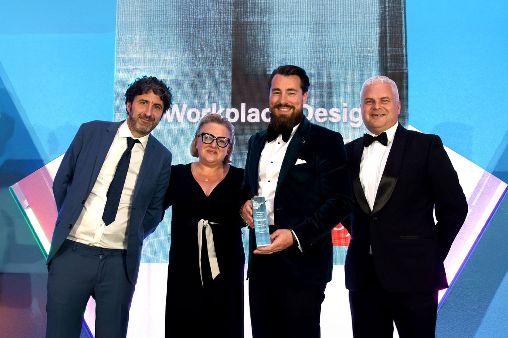 Four people collecting award in suits and ties