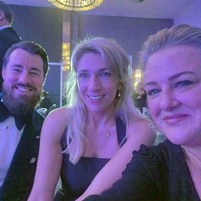 3 people smiling whilst taking a selfie in smart attire