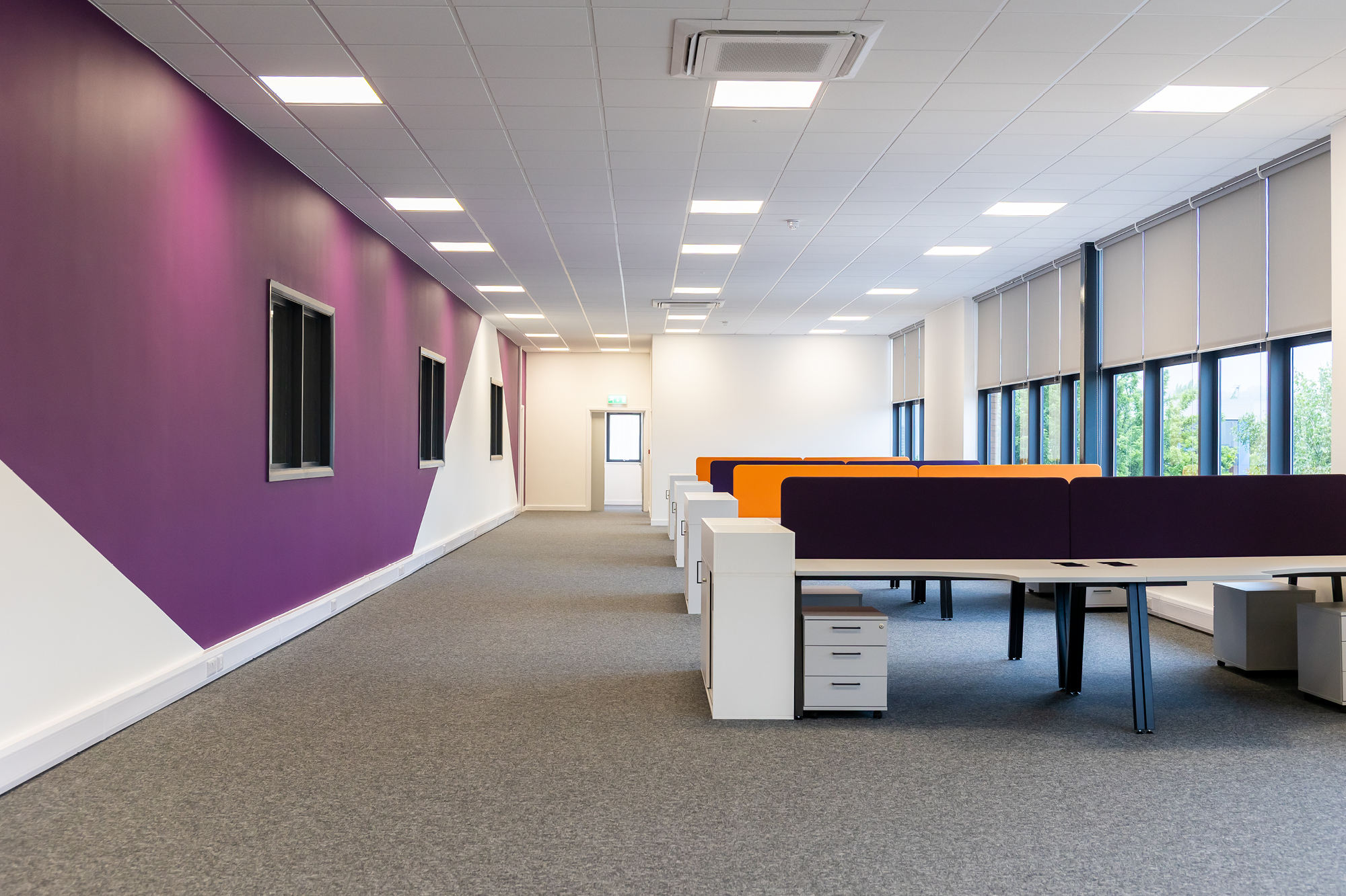 open office space with purple wall and desking area