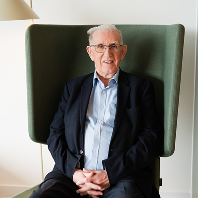 man smiling and sitting on chair with hands crossed