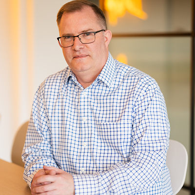 man with glasses sitting on stool with striped shirt