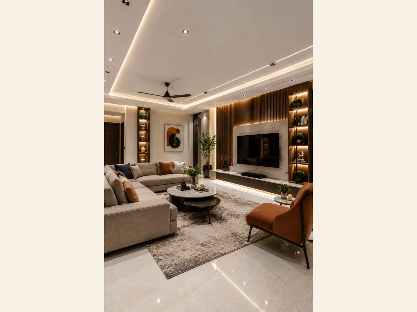 A warm modern living room pairing a beige sectional with a fluted wood and marble TV wall, lit shelving and terracotta accents.