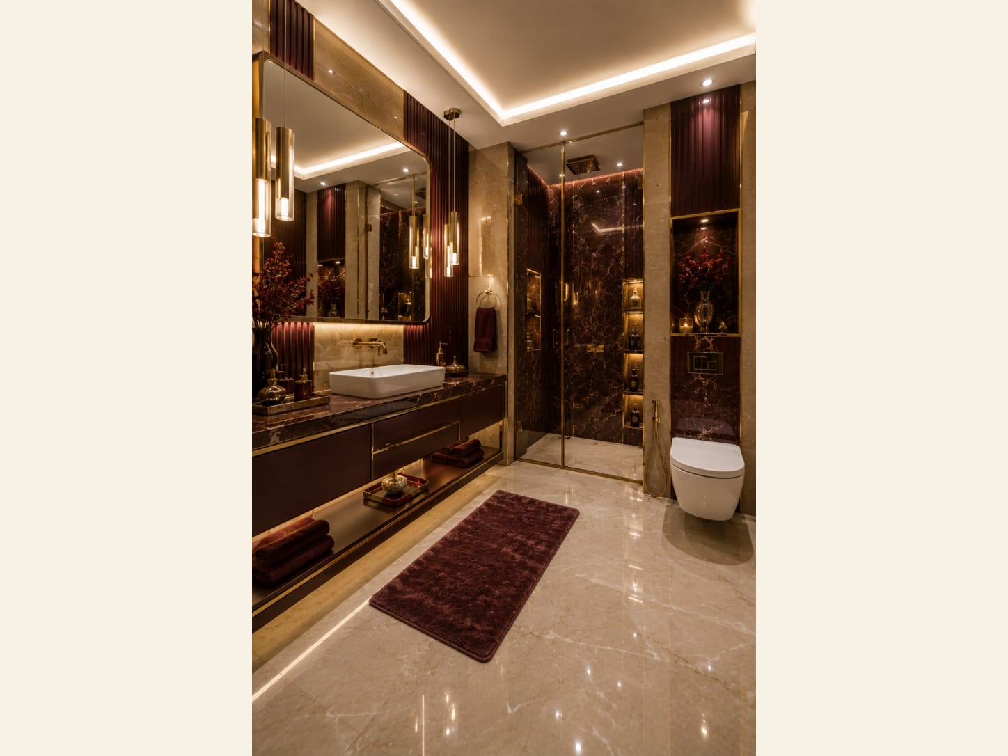 A Dramatic Maroon Marble and Gold Luxury Bathroom A moody, glamorous bathroom wrapped in maroon marble and brushed gold, with a walk-in shower, floating vanity and warm layered lighting.