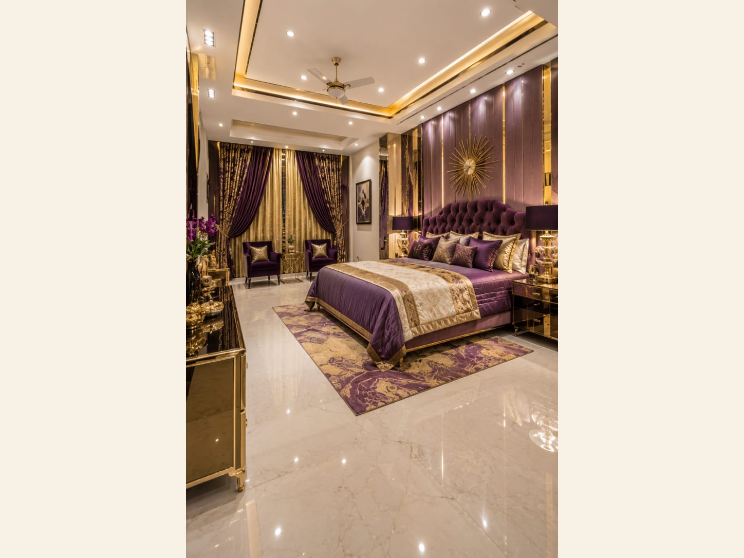 A Purple and Gold Glam Master Bedroom Fit for Royalty An opulent master bedroom drenched in purple velvet and gold, with a tufted headboard, sunburst wall art and mirrored nightstands.