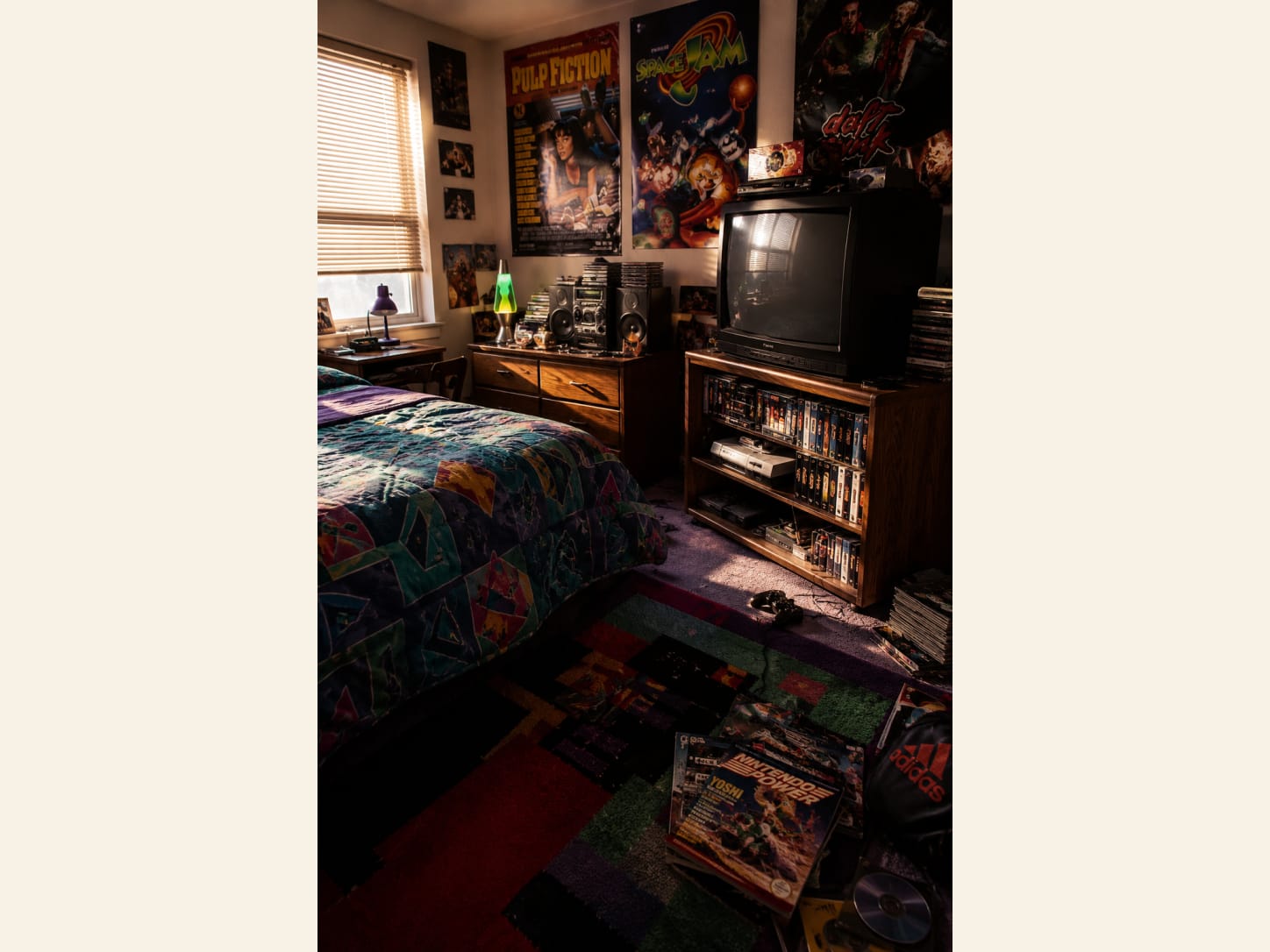 Give retro media a proper home instead of scattering props Retro 90s teen bedroom with movie posters, a CRT television, boombox, VHS shelves, geometric bedding and a patterned rug