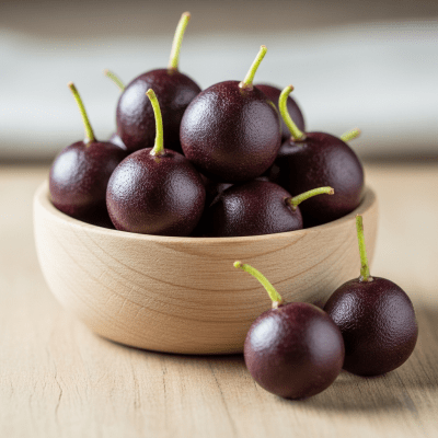 A high resolution image of several fresh Acai Berrys arranged in a simple bowl, representing their use within the taxonomy berries