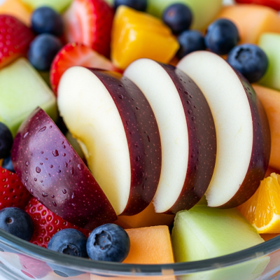 A photograph of a freshly sliced Arkansas Black of the taxonomy apples, presented as part of a fruit salad in a clear bowl