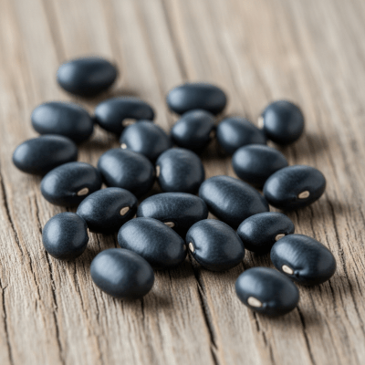 A handful of uncooked Black Bean beans (beans) scattered on a rustic wooden surface, photographed in natural light to emphasize their variety and color
