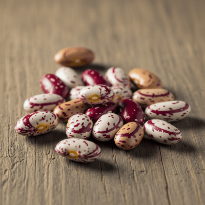 A handful of uncooked Calico Bean beans (beans) scattered on a rustic wooden surface, photographed in natural light to emphasize their variety and color