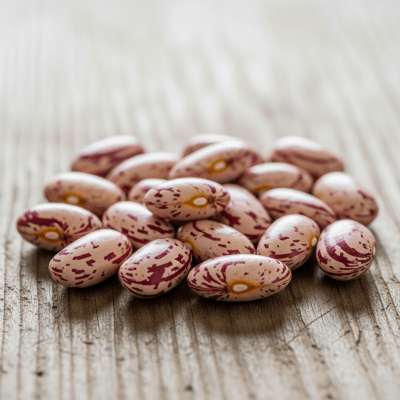 A handful of uncooked Cranberry Bean beans (beans) scattered on a rustic wooden surface, photographed in natural light to emphasize their variety and color