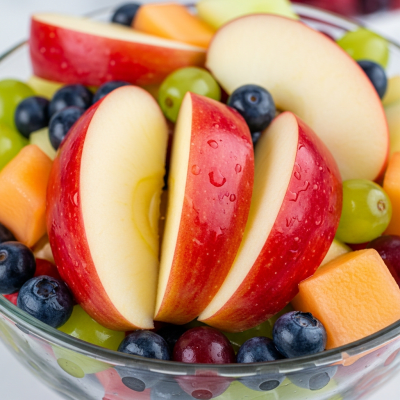 A photograph of a freshly sliced Enterprise of the taxonomy apples, presented as part of a fruit salad in a clear bowl