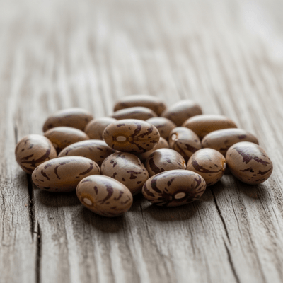 A handful of uncooked Field Bean beans (beans) scattered on a rustic wooden surface, photographed in natural light to emphasize their variety and color