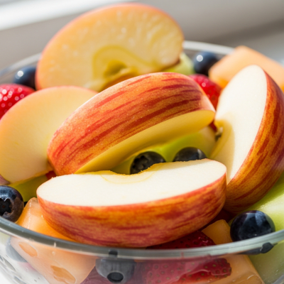 A photograph of a freshly sliced Gala of the taxonomy apples, presented as part of a fruit salad in a clear bowl
