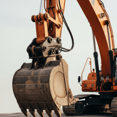 A close-up photograph focusing on the bucket and arm of a Hydraulic demolition / high-reach excavator (excavators), showing details such as hydraulic lines, metal textures, and wear marks