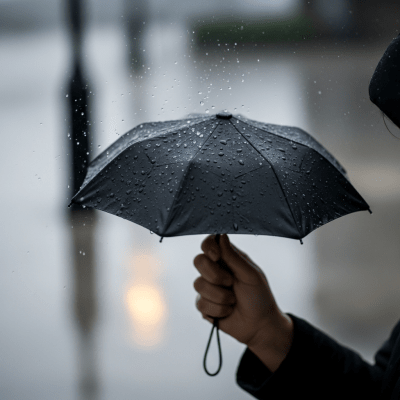 A realistic image of a Mini Umbrella (umbrellas) being used outdoors during a light rain, with droplets visible on the umbrella surface