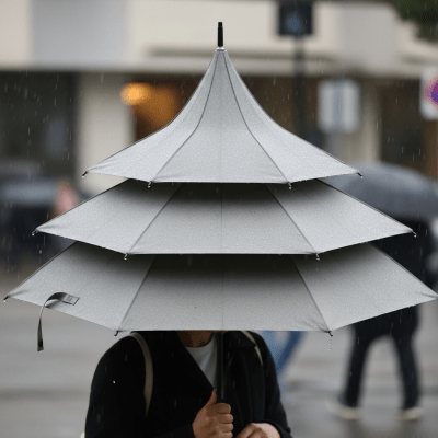 A realistic image of a Pagoda Umbrella (umbrellas) being used outdoors during a light rain, with droplets visible on the umbrella surface