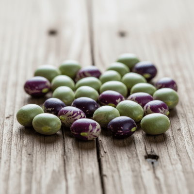 A handful of uncooked Purple Hull Pea beans (beans) scattered on a rustic wooden surface, photographed in natural light to emphasize their variety and color