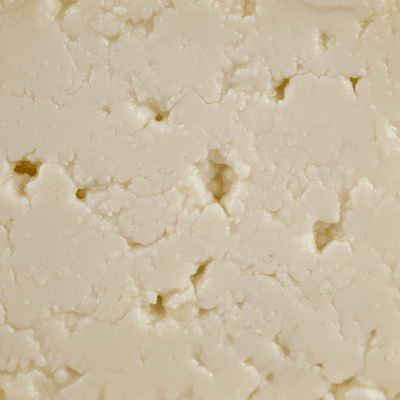A close-up macro photograph of the rind and surface texture of a Queso Fresco