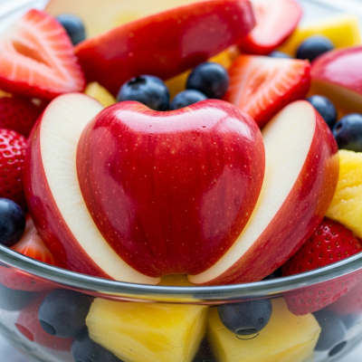 A photograph of a freshly sliced Red Delicious of the taxonomy apples, presented as part of a fruit salad in a clear bowl