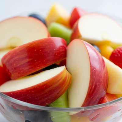 A photograph of a freshly sliced Rome of the taxonomy apples, presented as part of a fruit salad in a clear bowl
