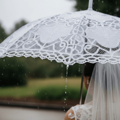 A realistic image of a Wedding Umbrella (umbrellas) being used outdoors during a light rain, with droplets visible on the umbrella surface
