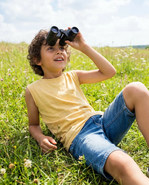 Boy with binoculars in grass