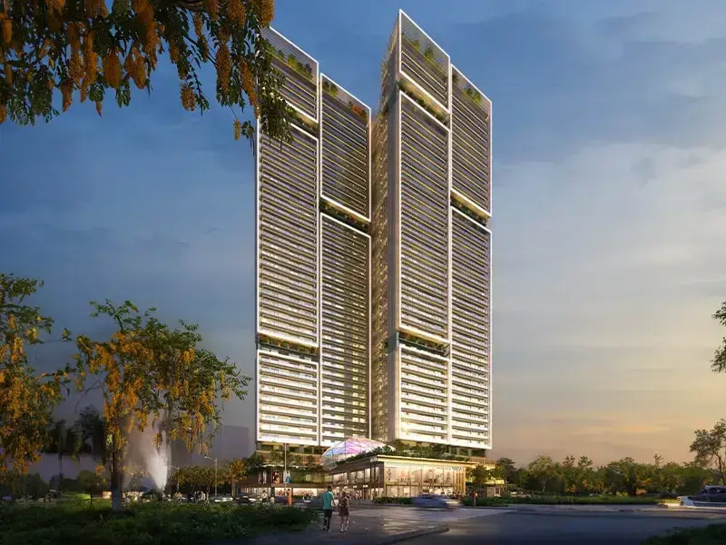 Two tall modern towers with glass facades, surrounded by greenery and a clear sky.