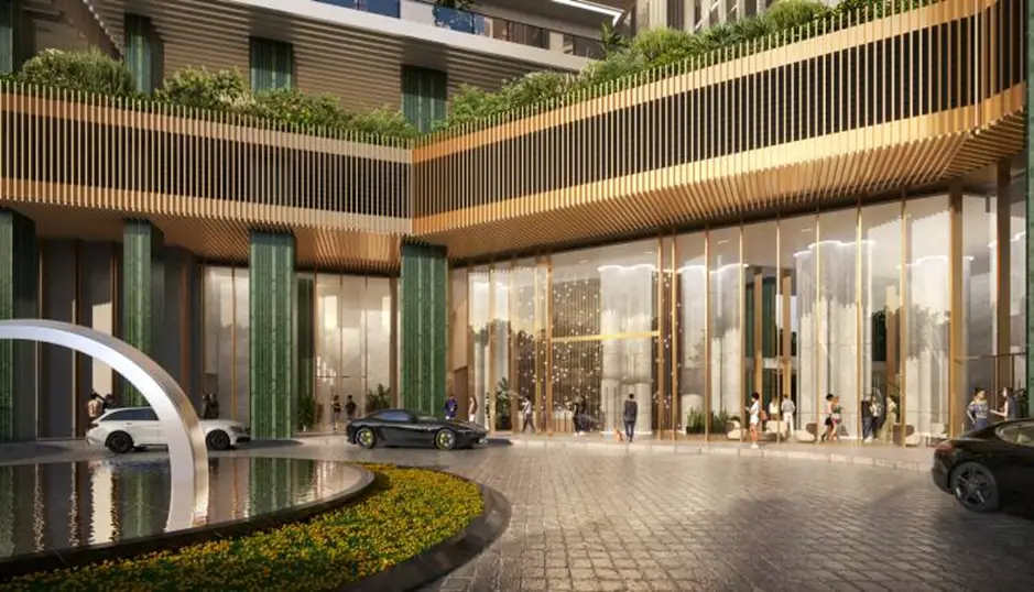 Modern building entrance with glass facade, greenery, and decorative fountain in foreground.