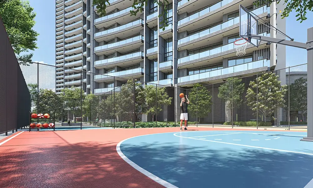A basketball court with a player shooting a ball near modern residential buildings and greenery.