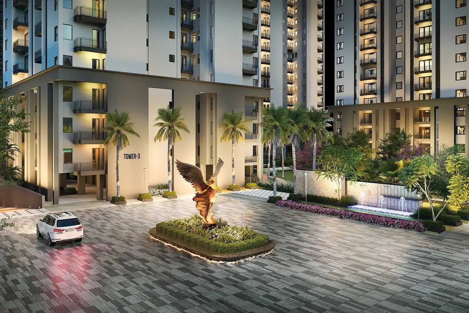 Modern residential building entrance with palm trees and a statue in the courtyard.