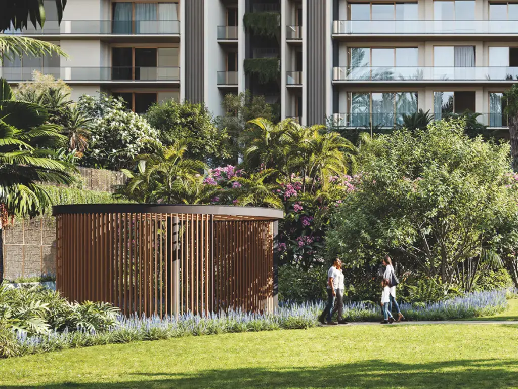 Two people walking in a lush garden with tropical plants and a wooden pavilion.